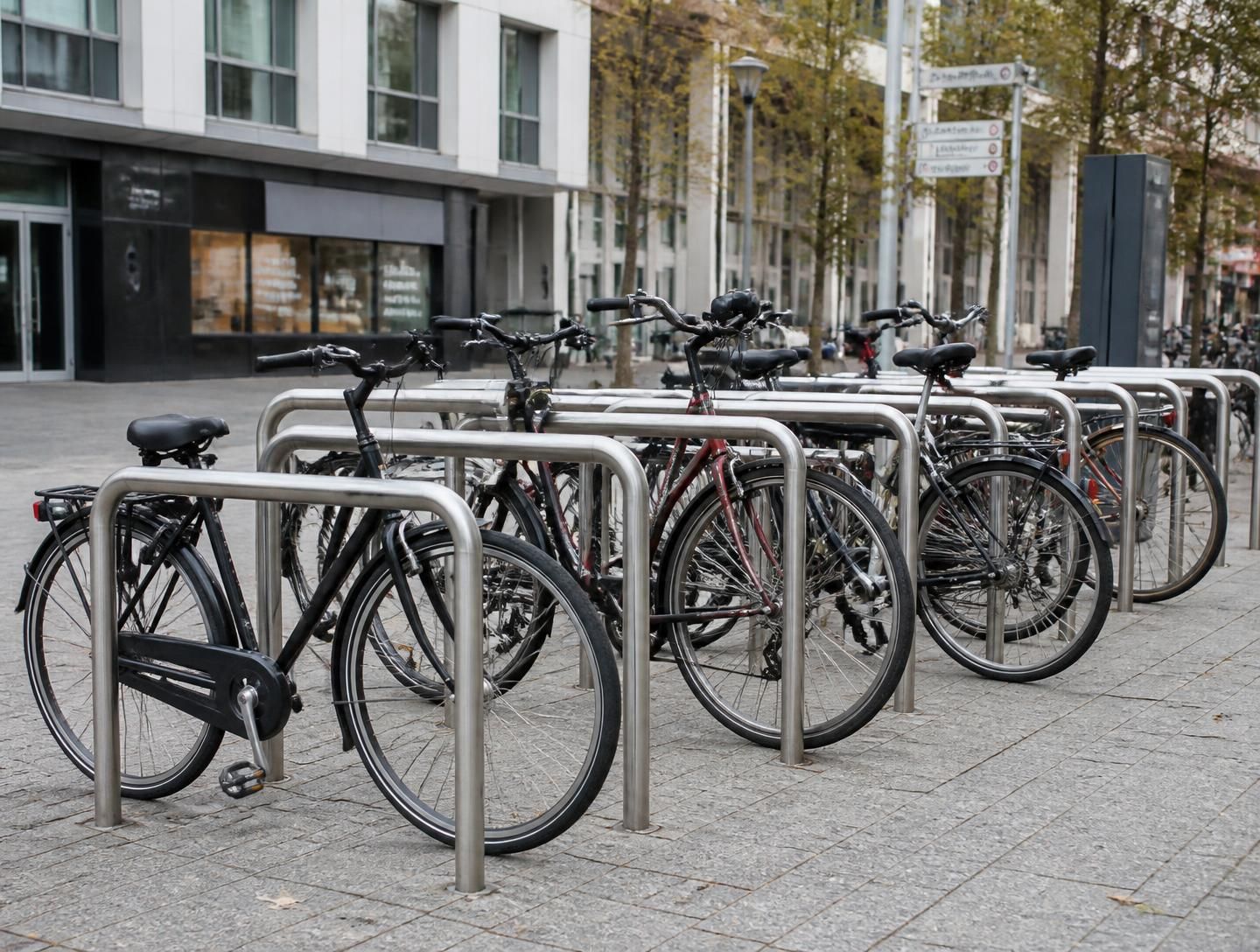 Aparcabicicletas de acero verde alineados en una acera urbana
