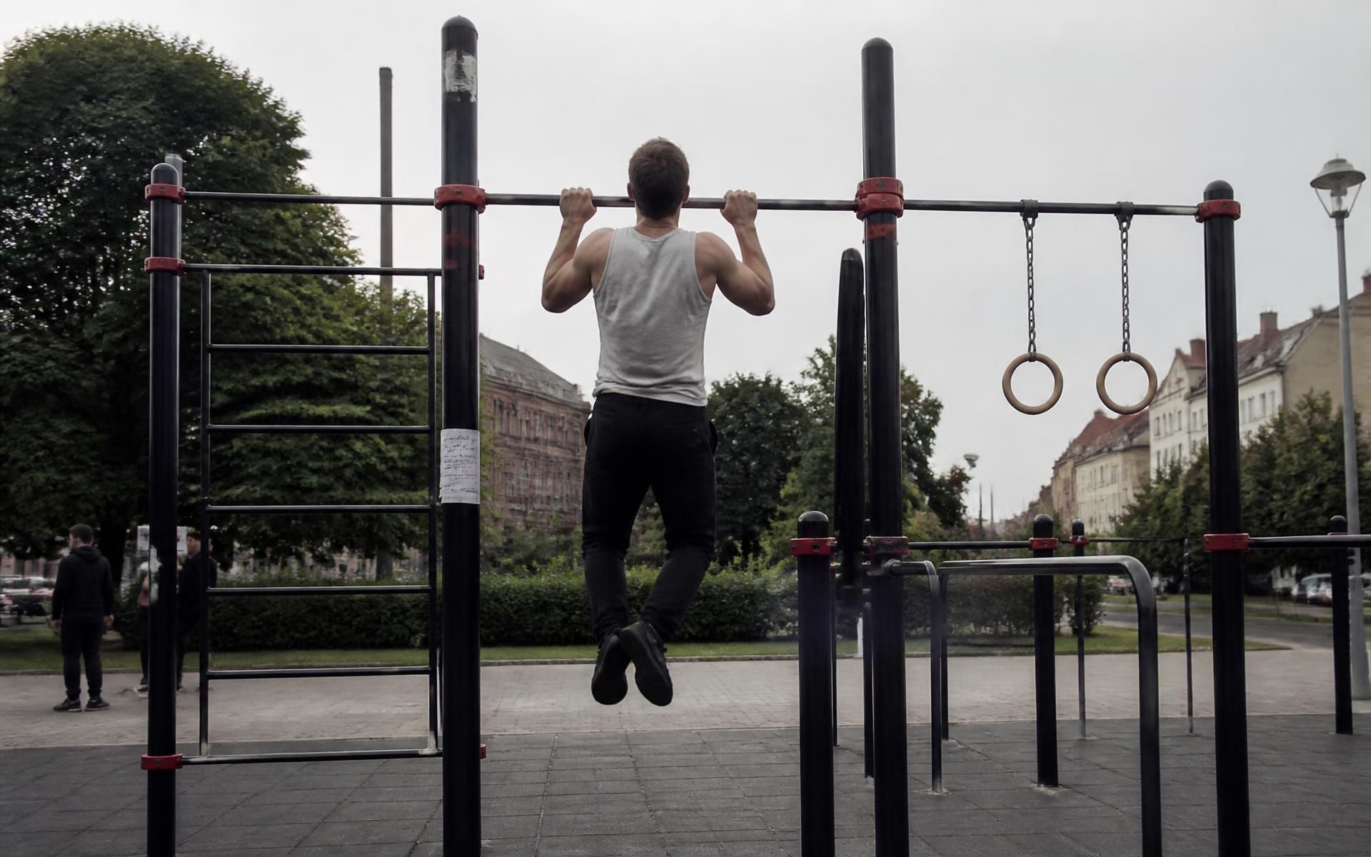 Estructura de calistenia y street workout en acero verde sobre pavimento de seguridad en un parque urbano