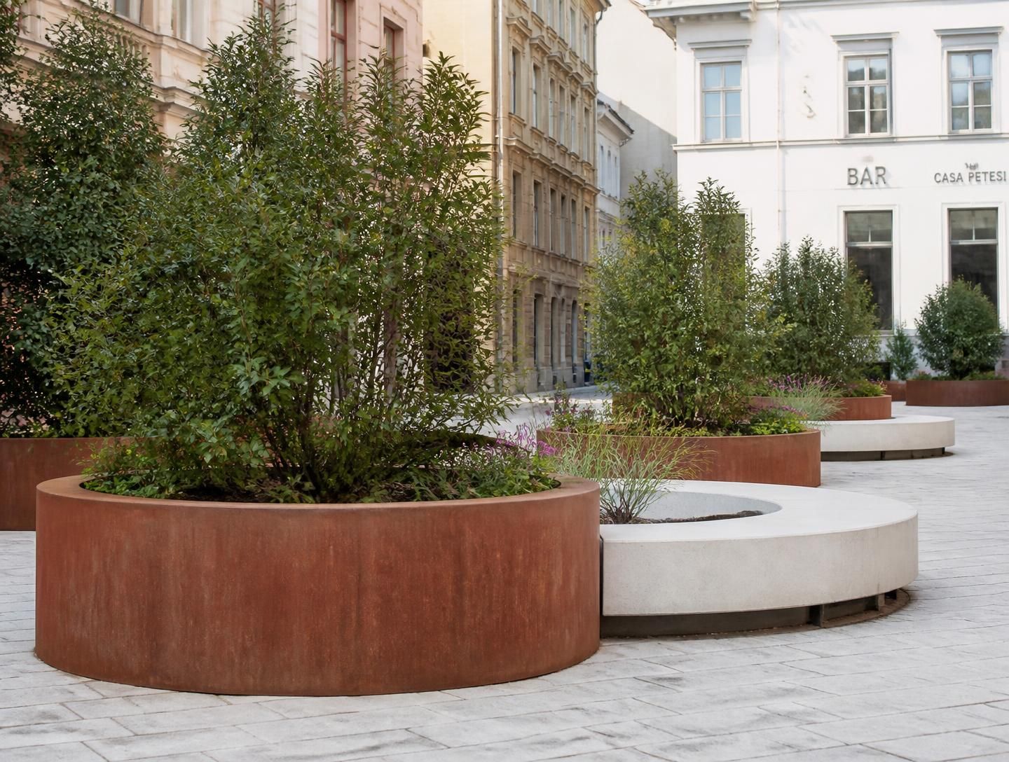 Jardineras urbanas con gramíneas en una plaza pavimentada