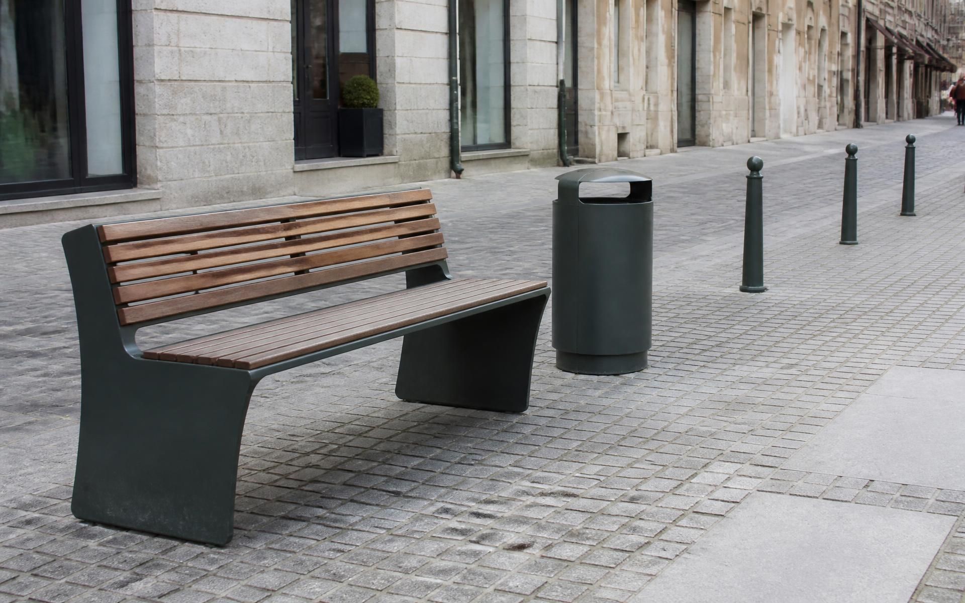 Banco urbano de acero verde y madera junto a papelera en un parque